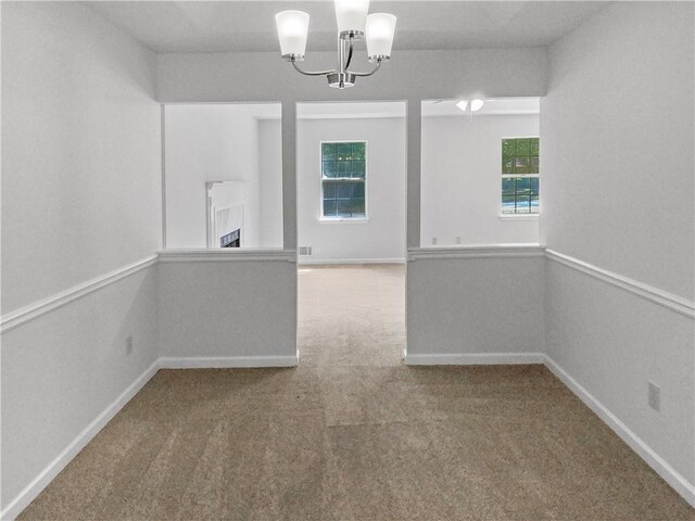 carpeted spare room with a notable chandelier