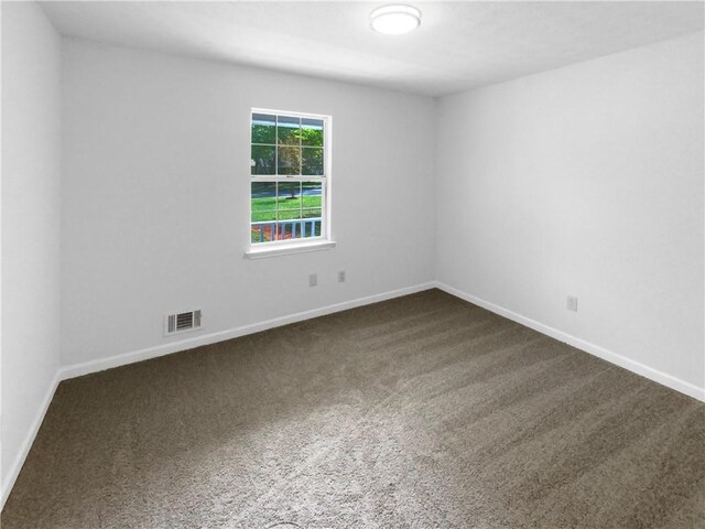 spare room featuring dark colored carpet