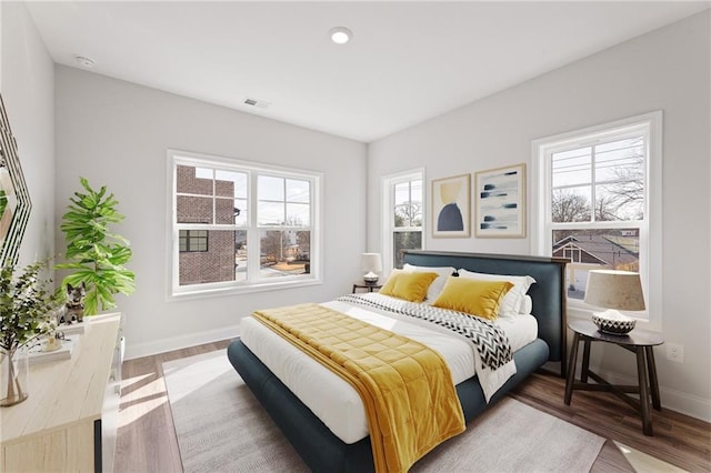 bedroom with multiple windows and hardwood / wood-style floors