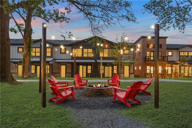 playground at dusk featuring a yard and a fire pit