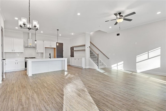 unfurnished living room featuring light wood-type flooring, ceiling fan with notable chandelier, and ornamental molding