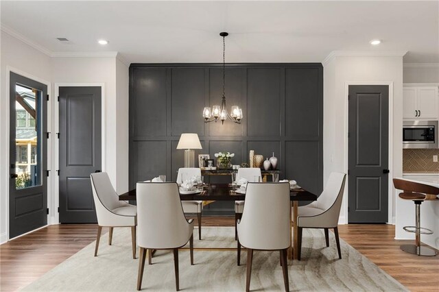 dining space featuring light hardwood / wood-style flooring, a notable chandelier, and ornamental molding