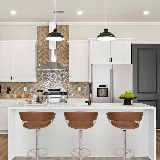 kitchen featuring white cabinets, stainless steel range oven, white fridge with ice dispenser, and an island with sink