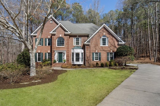 colonial home featuring a front yard and brick siding