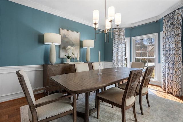 dining room with wood finished floors, a wainscoted wall, crown molding, and an inviting chandelier