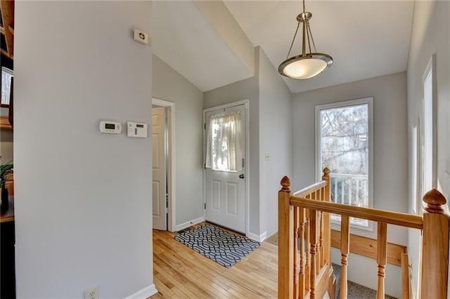 foyer featuring light wood finished floors, lofted ceiling, and baseboards