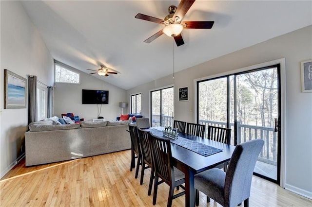 dining space featuring ceiling fan, lofted ceiling, light wood-style flooring, healthy amount of natural light, and baseboards