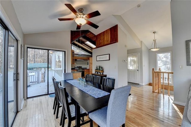 dining space with ceiling fan, light wood-style flooring, high vaulted ceiling, and baseboards