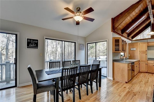 dining space featuring ceiling fan, light wood finished floors, baseboards, high vaulted ceiling, and beam ceiling
