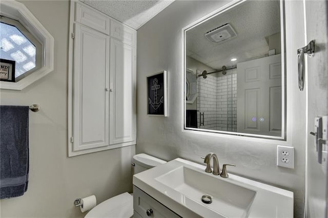 full bath with toilet, a tile shower, vanity, and a textured ceiling