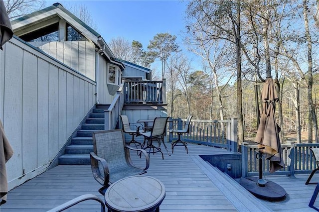 wooden terrace featuring outdoor dining space and stairs