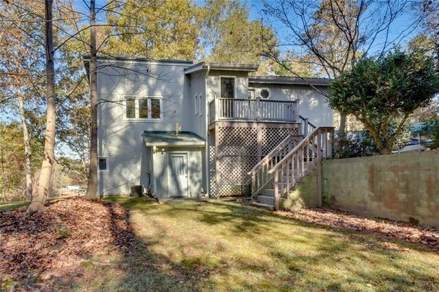 back of property with a lawn, a wooden deck, and stairs