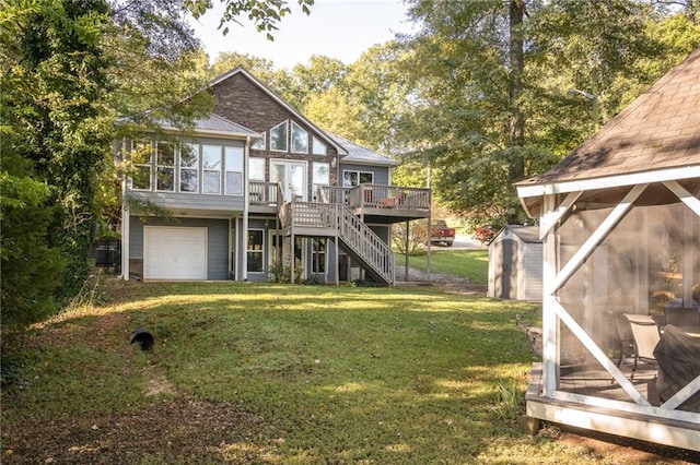 rear view of house with a garage, a lawn, and a wooden deck