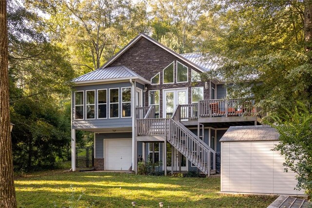 back of property featuring a garage, a deck, a yard, and a sunroom