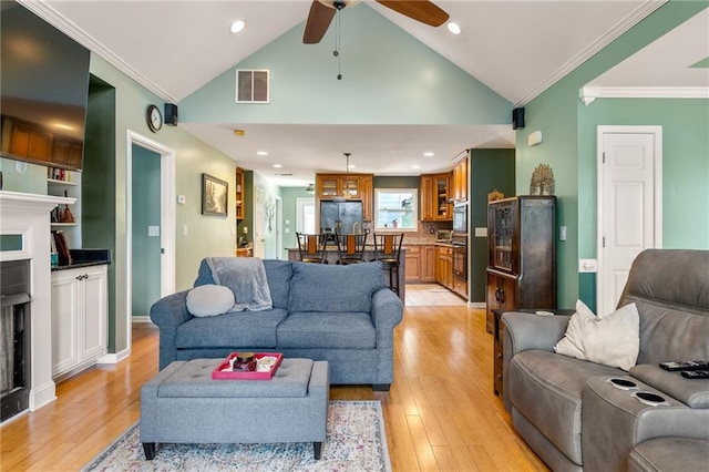 living room with ornamental molding, high vaulted ceiling, ceiling fan, and light hardwood / wood-style flooring