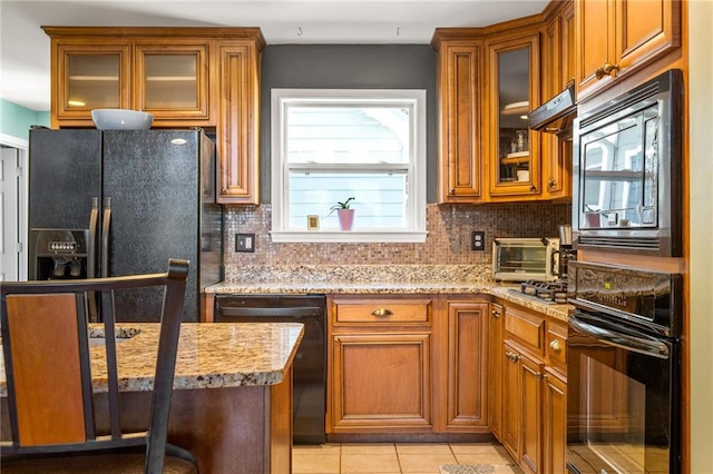 kitchen with black appliances, light stone countertops, decorative backsplash, ventilation hood, and light tile patterned floors