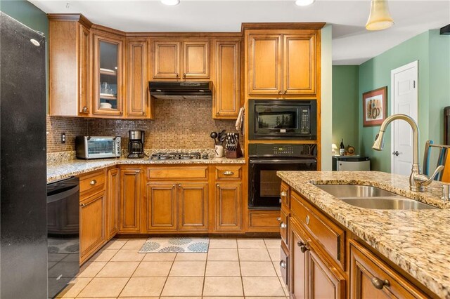 kitchen with light tile patterned floors, sink, backsplash, black appliances, and light stone countertops