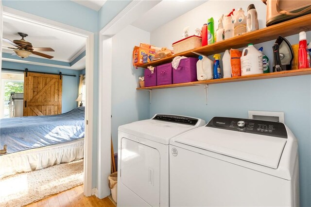 clothes washing area featuring ceiling fan, separate washer and dryer, light hardwood / wood-style floors, and a barn door