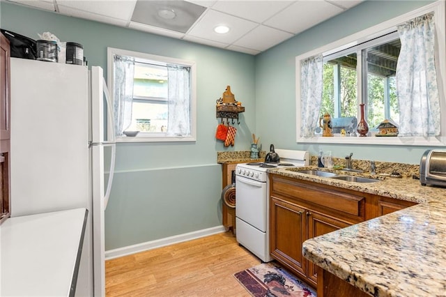 kitchen featuring light stone countertops, a paneled ceiling, white appliances, sink, and light hardwood / wood-style flooring