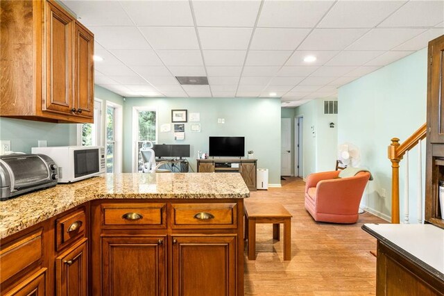 kitchen featuring light stone counters, a paneled ceiling, and light hardwood / wood-style floors