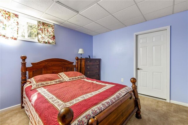 bedroom featuring light carpet and a drop ceiling