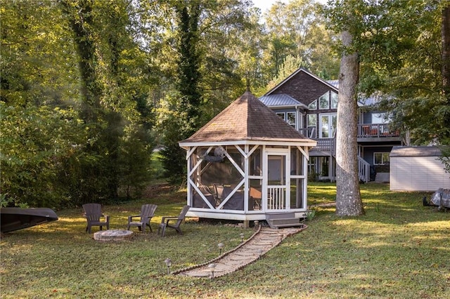 back of property with a storage shed, a fire pit, and a lawn