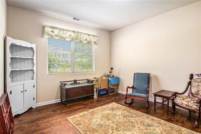 living area with baseboards, visible vents, and wood finished floors