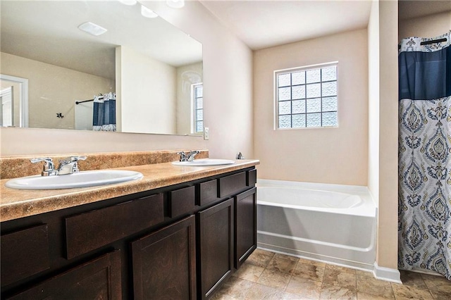 full bath featuring double vanity, baseboards, a sink, and a garden tub