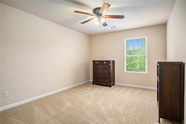 spare room featuring a ceiling fan, baseboards, visible vents, and light carpet