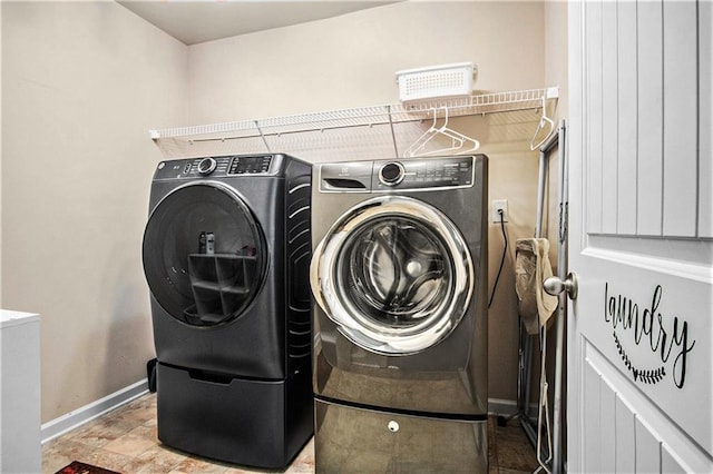 clothes washing area with laundry area, stone finish flooring, baseboards, and washer and dryer