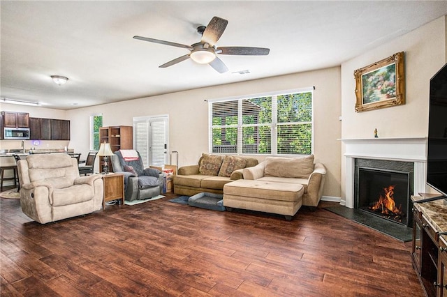 living room featuring a high end fireplace, visible vents, ceiling fan, and dark wood-type flooring