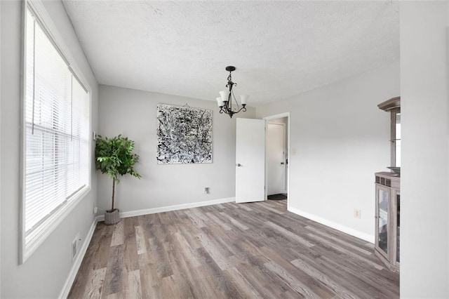 2103 Blue Creek Ct, Conley, GA 30288 - unfurnished living room with a chandelier, wood finished floors, plenty of natural light, and a textured ceiling