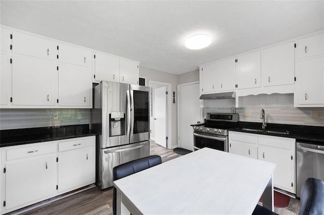 2103 Blue Creek Ct, Conley, GA 30288 - kitchen with appliances with stainless steel finishes, under cabinet range hood, dark wood-style floors, white cabinetry, and decorative backsplash