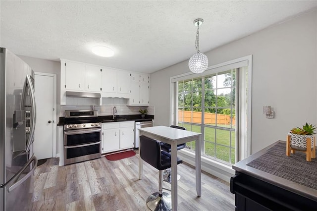 2103 Blue Creek Ct, Conley, GA 30288 - kitchen with stainless steel appliances, light wood-type flooring, white cabinetry, and a textured ceiling