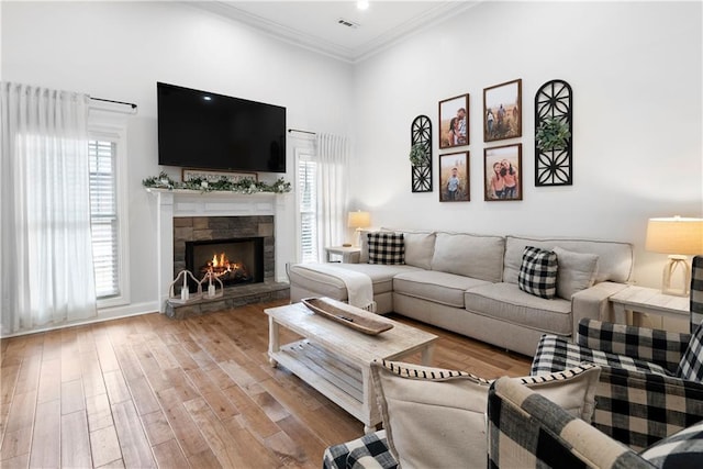 living room featuring plenty of natural light, crown molding, a towering ceiling, and wood finished floors