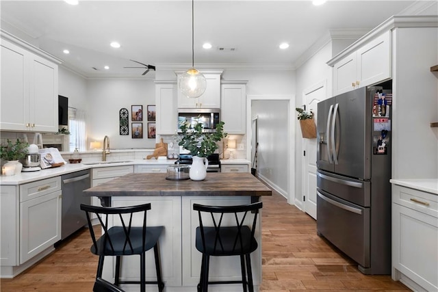 kitchen with visible vents, a sink, appliances with stainless steel finishes, a breakfast bar area, and light wood finished floors