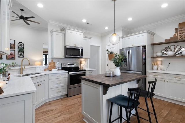 kitchen featuring wood counters, crown molding, appliances with stainless steel finishes, and a sink