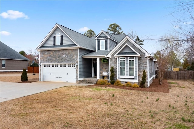 traditional-style home featuring fence, concrete driveway, a front yard, stone siding, and an attached garage