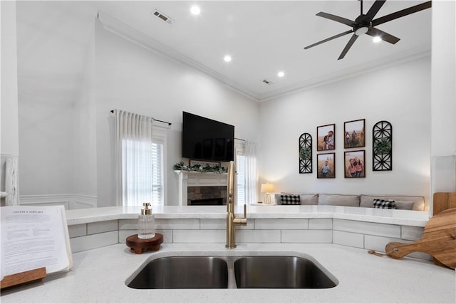 kitchen featuring visible vents, crown molding, open floor plan, and a sink