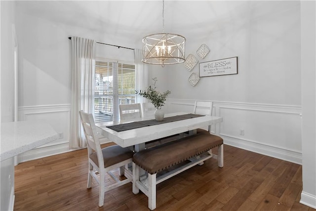 dining room featuring a notable chandelier, wainscoting, a decorative wall, and wood finished floors