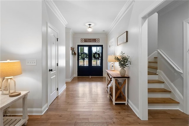 foyer featuring light wood finished floors, stairs, baseboards, and ornamental molding