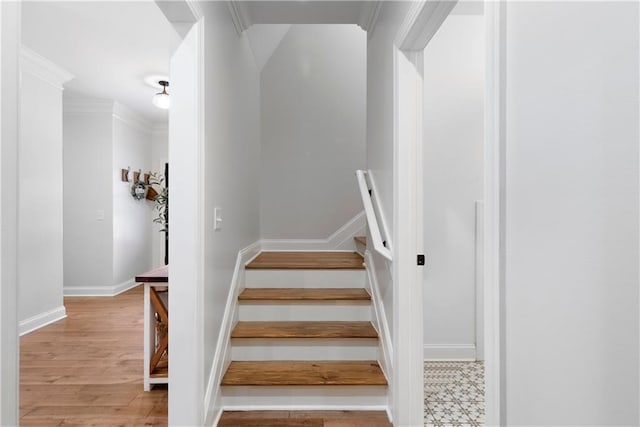 stairway featuring wood finished floors, baseboards, and ornamental molding