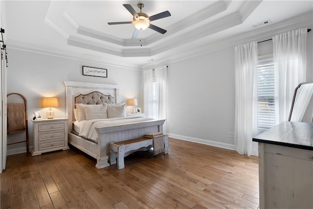 bedroom featuring visible vents, a raised ceiling, hardwood / wood-style floors, and ornamental molding