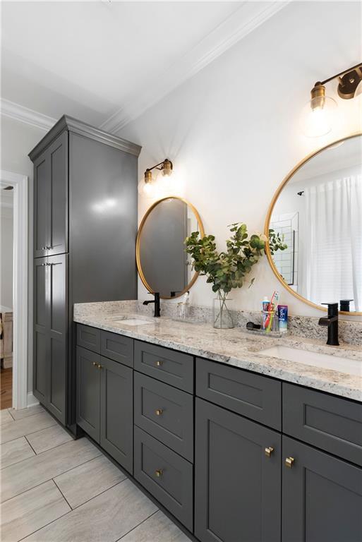 bathroom featuring crown molding, double vanity, and a sink