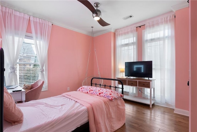 bedroom with visible vents, multiple windows, hardwood / wood-style floors, and ornamental molding