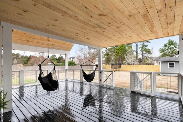 wooden deck with a trampoline and a fenced backyard