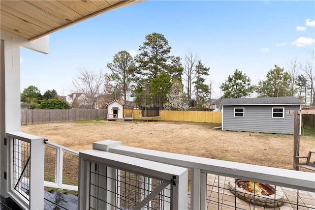 view of yard with a trampoline, a fenced backyard, and an outdoor fire pit