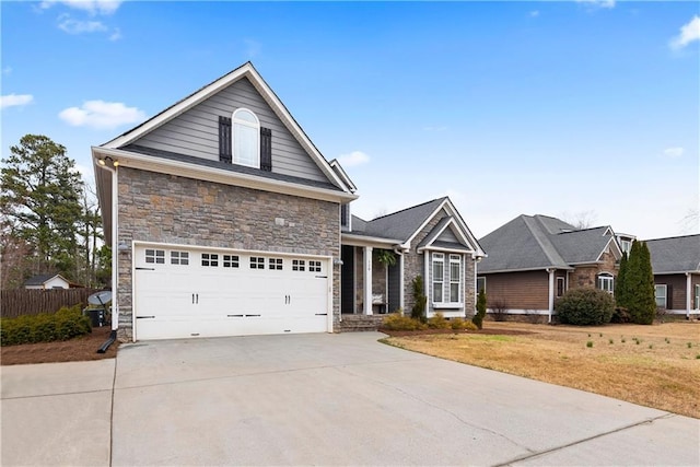 view of front facade with stone siding, concrete driveway, and fence