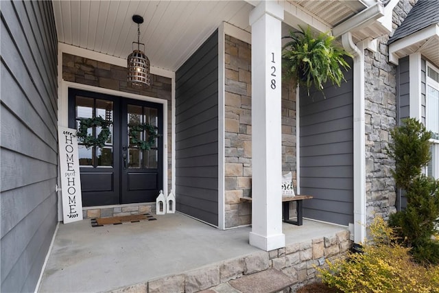 property entrance with a porch, french doors, and stone siding