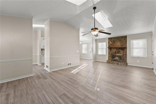 unfurnished living room featuring hardwood / wood-style flooring, a stone fireplace, a textured ceiling, and a wealth of natural light